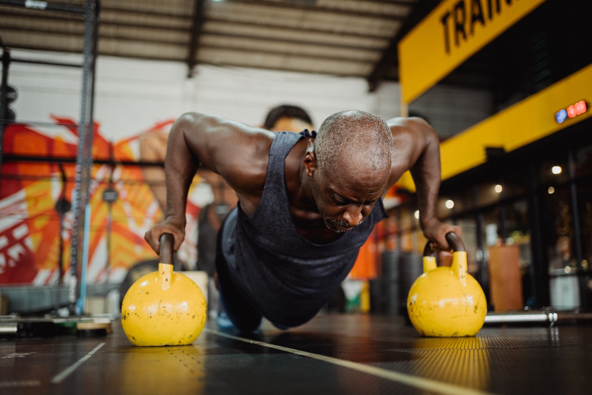 hombre haciendo flexiones con kettlebell amarillo